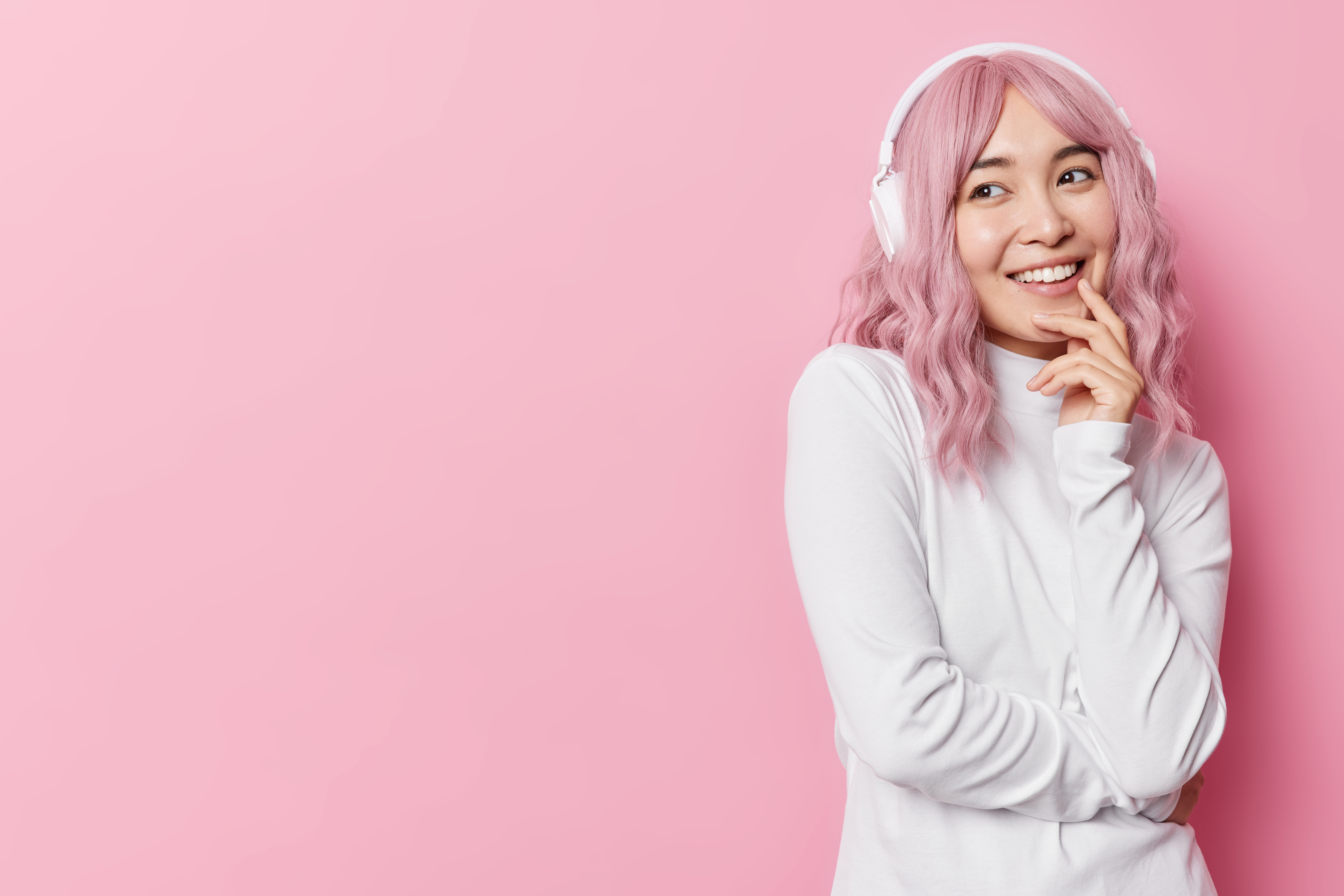happy-thoughtful-asian-woman-smiles-pleasantly-listens-audiotrack-via-stereo-headphones-wears-casual-white-jumper-isolated-pink-background-with-copy-space-away-listening-favorite-tunes.jpg